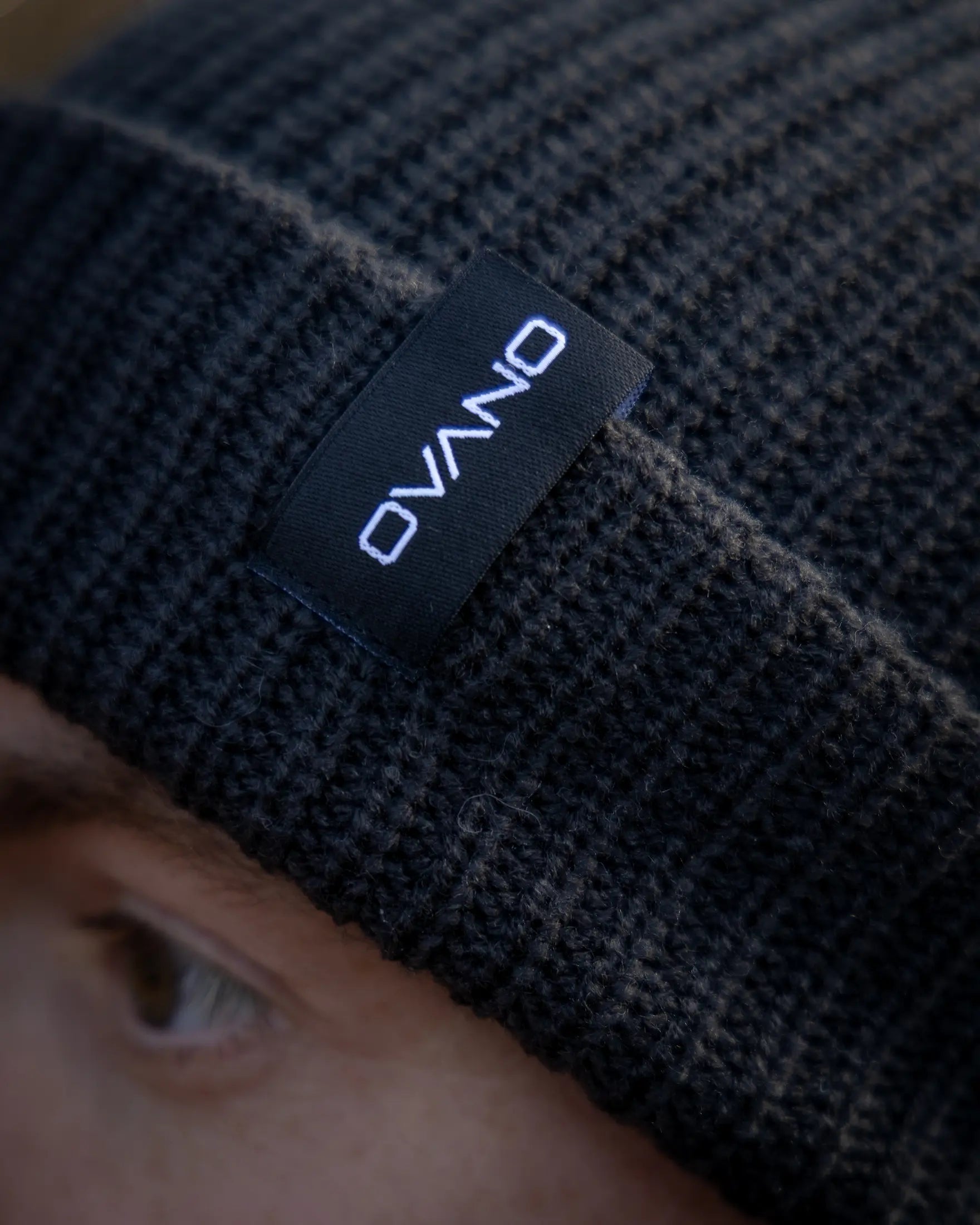 Black knit beanie with 'Ovano' label on a blurred background