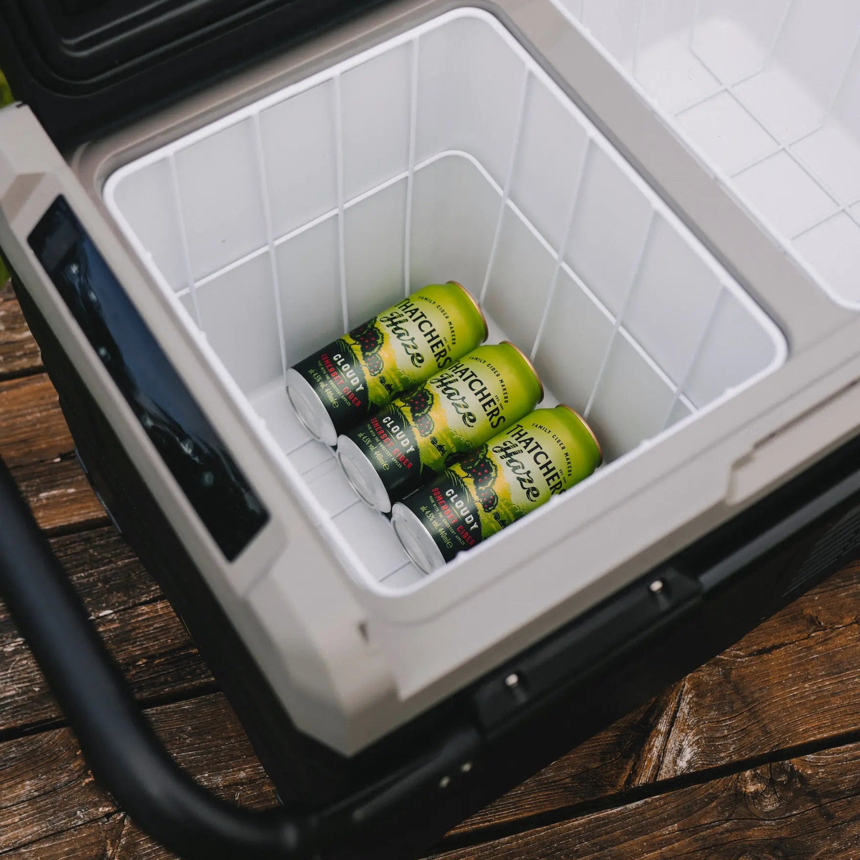 Cooler box with green Thatchers haze cans on a wooden surface