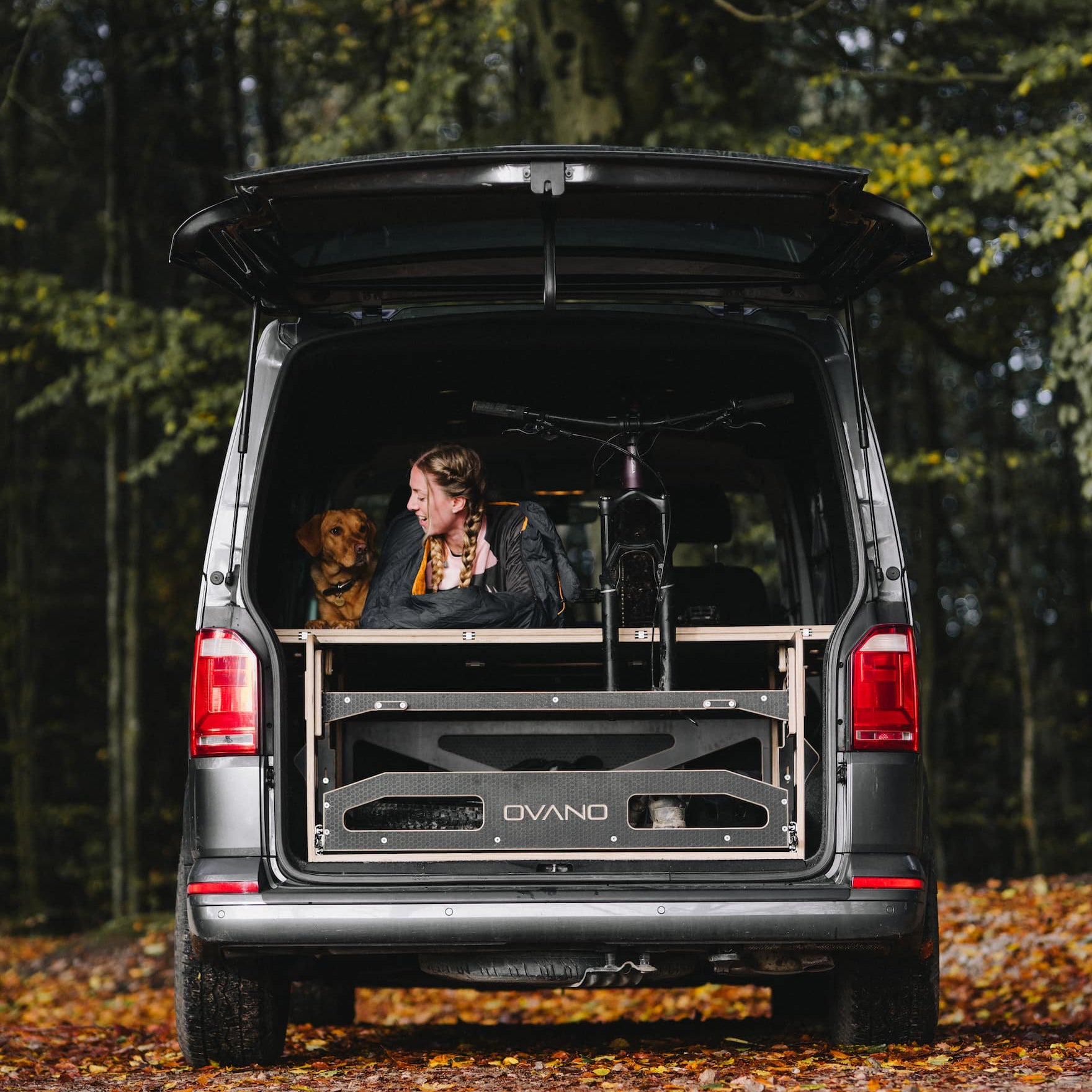 Woman and dog in Transporter, led next to a mountain bike.