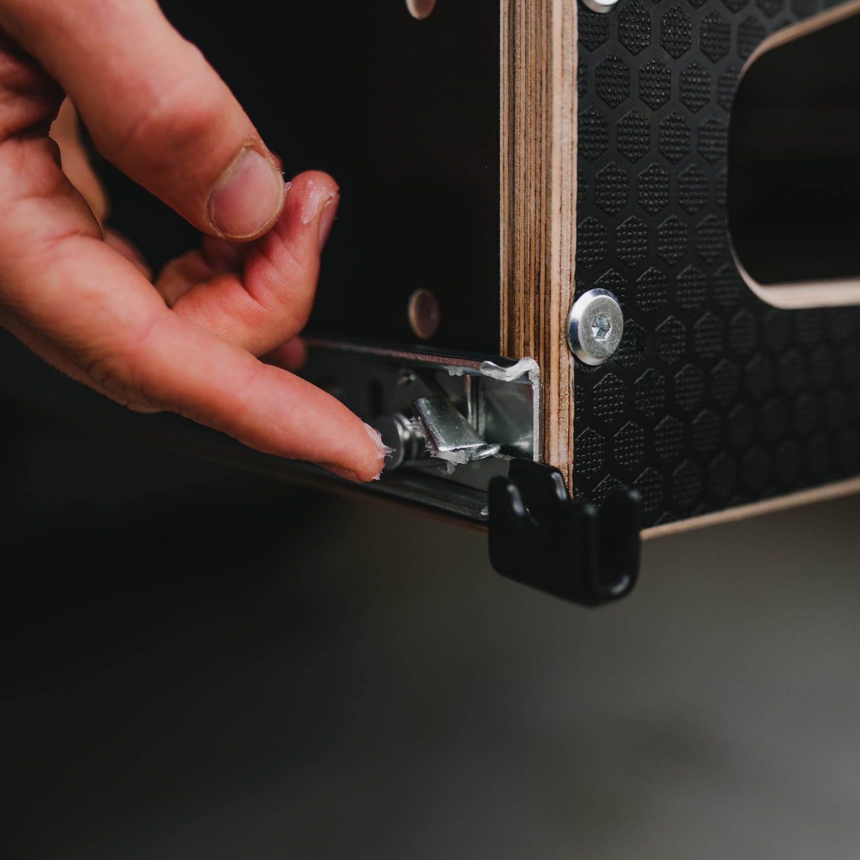 Hand opening a wooden box with metal clasp on a dark background