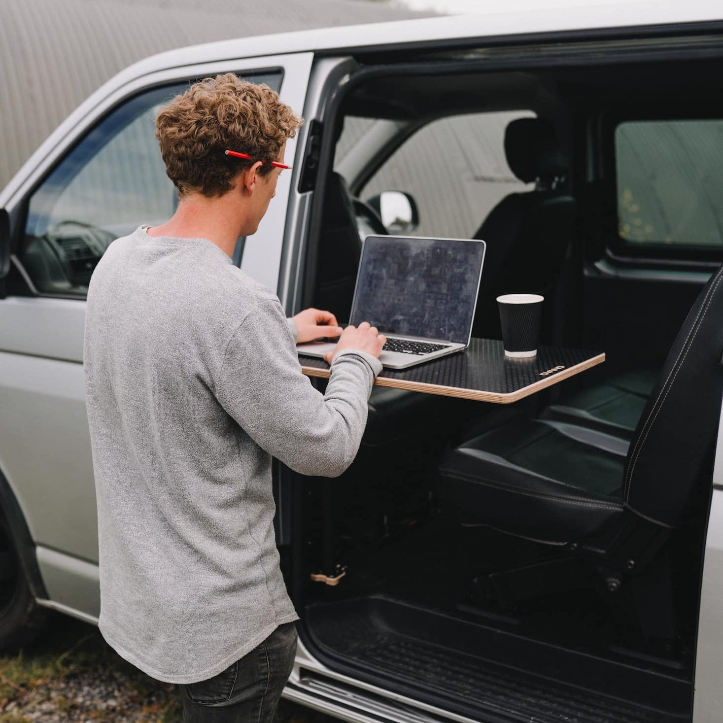 Man shown stood outside van using Ovano table as a laptop desk