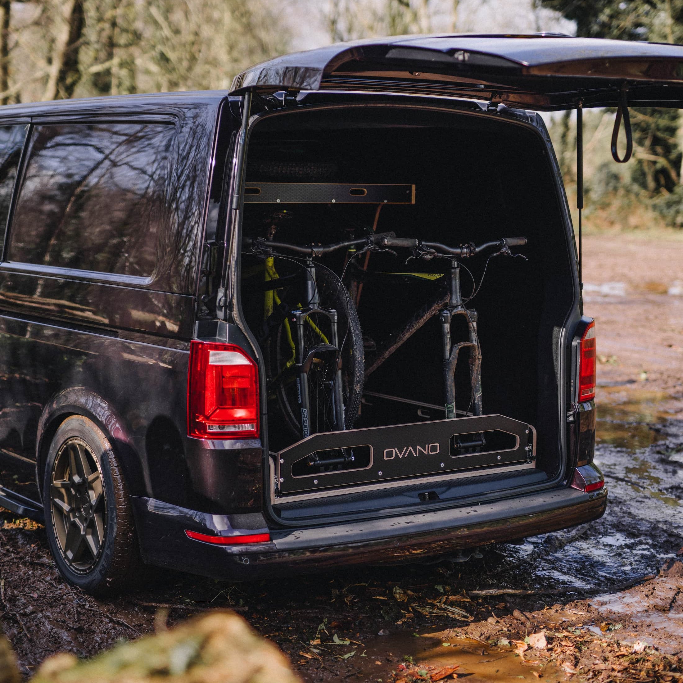 Black van with open tailgate, showing an Ovano bike rack with MTB's.