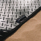 Black ovano rubber mat with embroidered label, displayed on sand