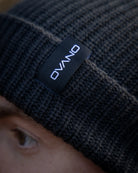 Black knit beanie with 'Ovano' label on a blurred background