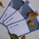 Ovano gift vouchers laid out on grey mottled floor with autumnal leaves