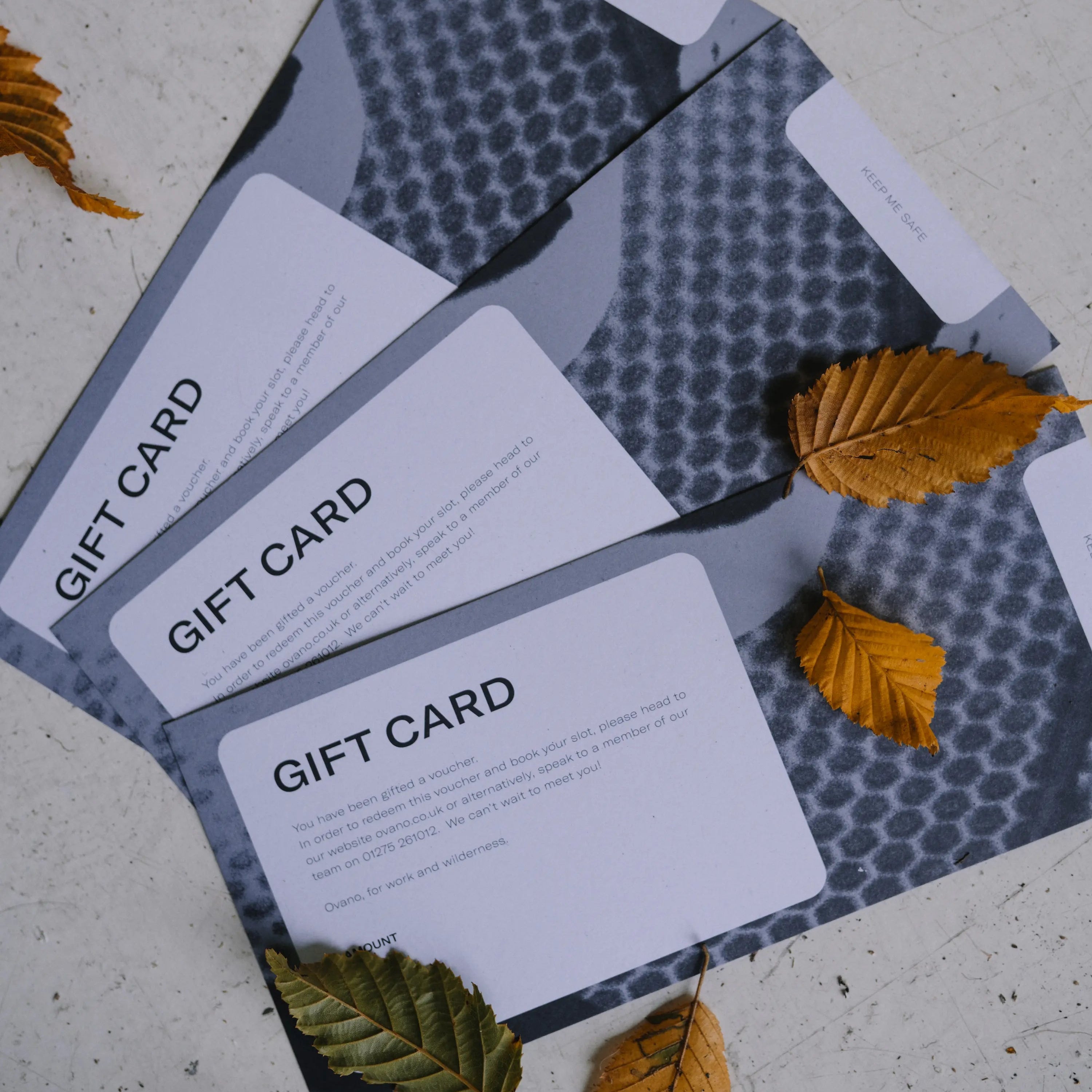Ovano gift vouchers laid out on grey mottled floor with autumnal leaves