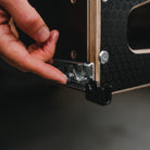 Hand opening a wooden box with metal clasp on a dark background