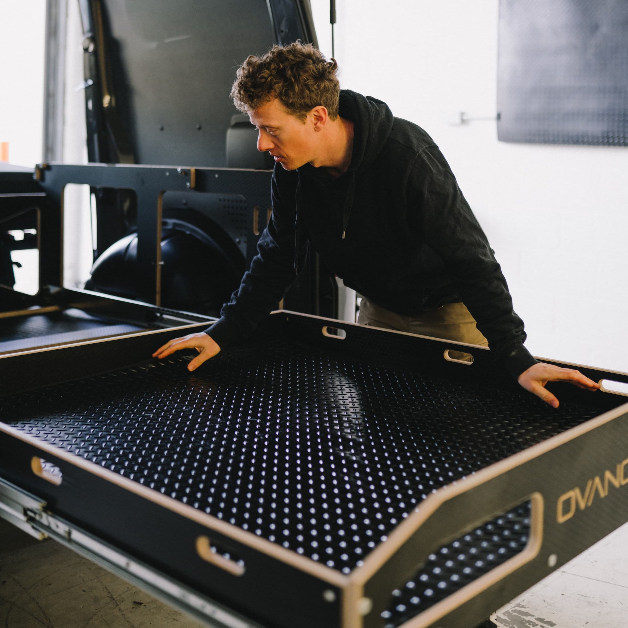 Person laying a black ovano rubber mat into a switch xl drawer.